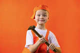 funny builder boy holding a hammer on an orange background