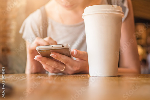 A girl is sitting with a phone in a cafe, a coffee house