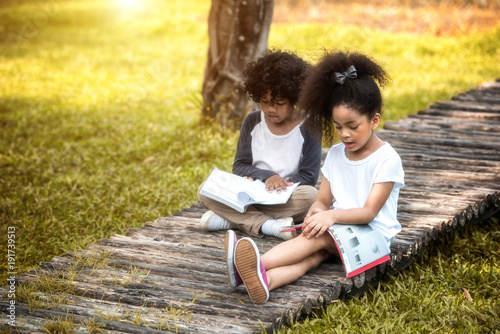 Children are reading happily together in the garden. Soft focus concept.
