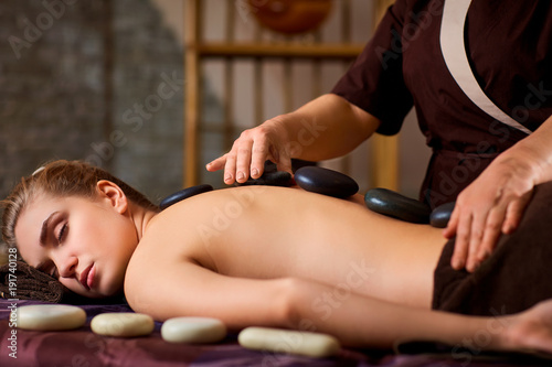 Stone massage back spa for a woman in the beauty center.