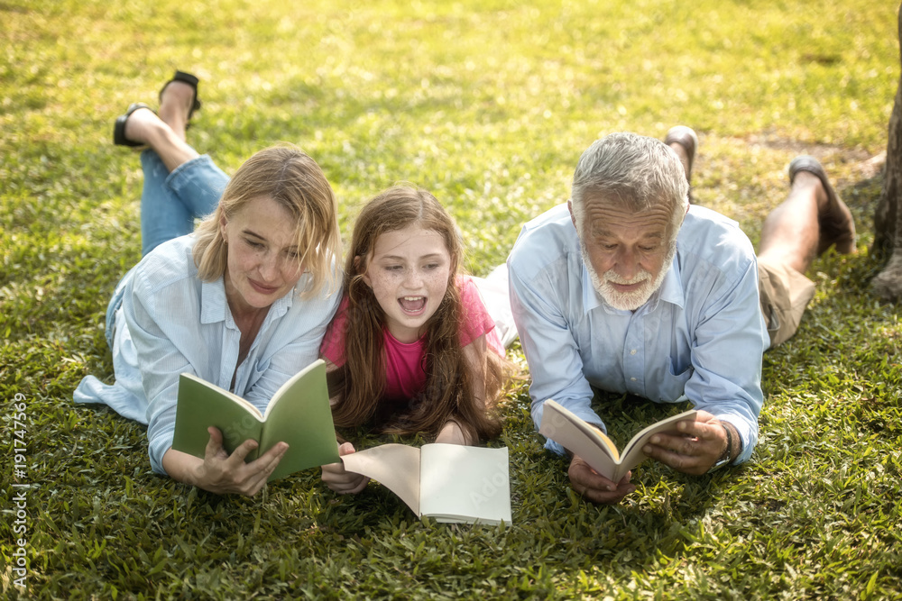 Family is reading happily together in the garden.Soft focus concept. Family is reading happily together in the garden.Soft focus concept.