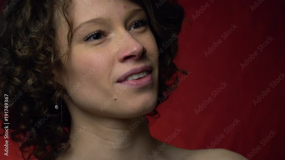 A girl with curly hair smiles cunningly and looks around A girl with curly hair smiles cunningly and looks around