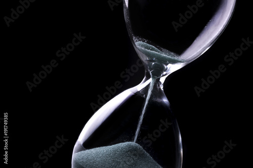 Sand running through the bulbs of an hourglass photo