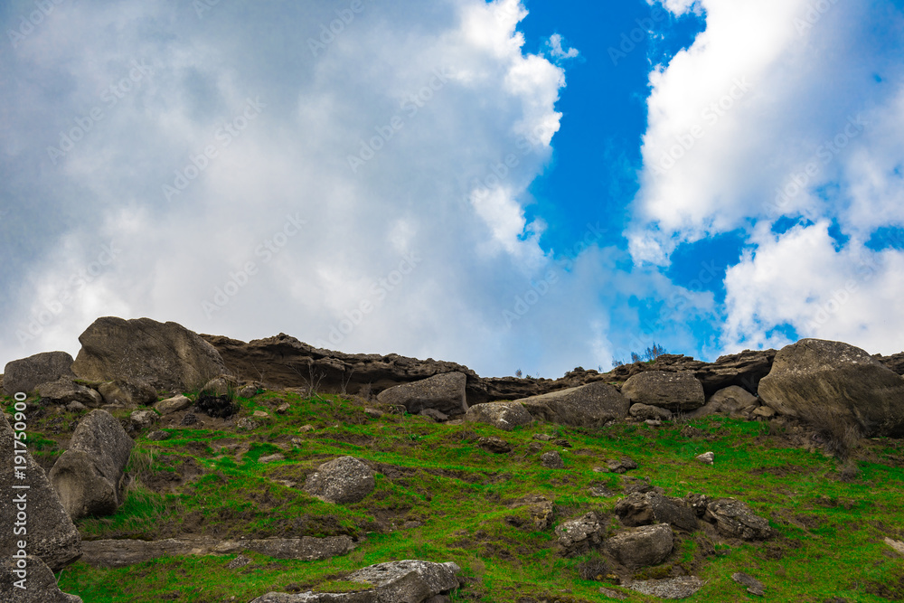 Fototapeta premium Rocks fragments in the highlands, green meadow