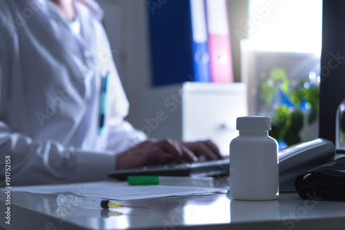 Fake doctor, quack or charlatan in hospital office. Medical crime, illegal health care, insurance fraud, negligence, treatment error or malpractice. Man in dark hospital typing computer prescription.