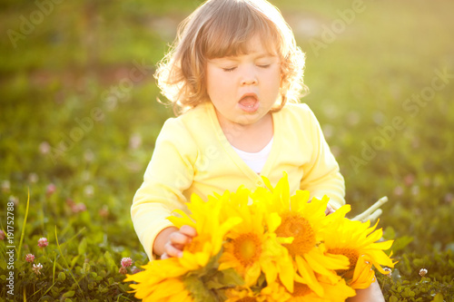 Happy child with bouquet of beautiful sunflowers. © Alinsa