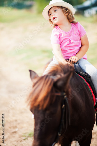 Cute toddler girl riding a horse.