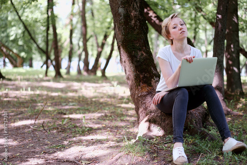 Woman typing on a laptop in the forest photo