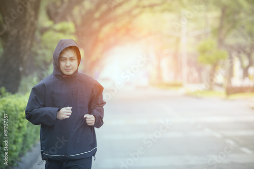 young man morning exercise by running on town street with beautiful light background