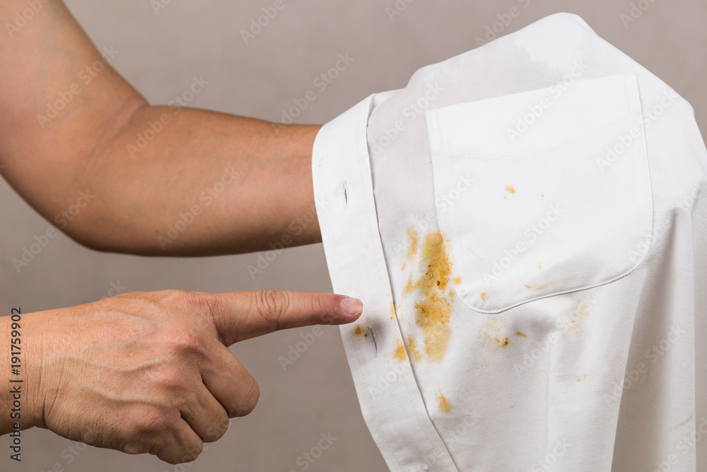 Person pointing to spilled curry stain on white shirt. - obrazy, fototapety, plakaty 