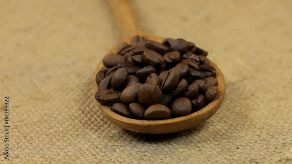 Close-up, spoon rotation with a pile of coffee beans lying on burlap. Close-up, spoon rotation with a pile of coffee beans lying on burlap.