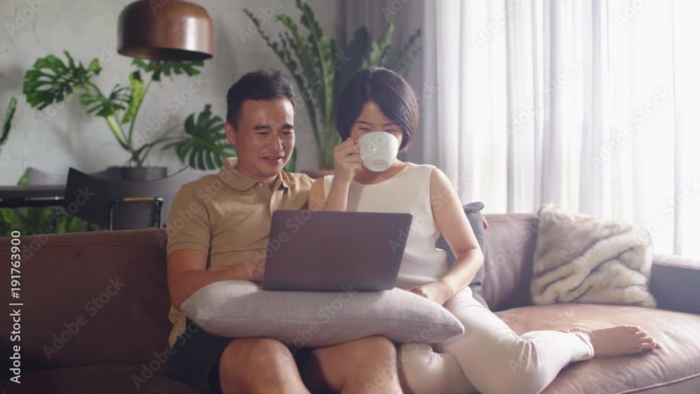 Happy Asian couple looking at the computer together at home. Happy Asian couple looking at the computer together at home.