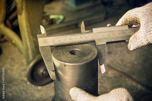 Worker using  vernier caliper measurement iron in workshop.