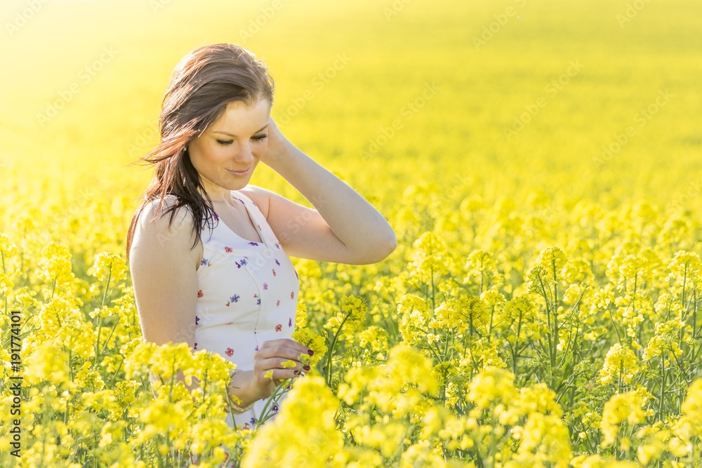 Beautiful youth woman with flower in summer meadow looking down. Beautiful girl eyes closed in yellow flowers field infinite horizon. Sunny sun sunshine and authentic lifestyle in windy weather hair Beautiful youth woman with flower in summer meadow looking down. Beautiful girl eyes closed in yellow flowers field infinite horizon. Sunny sun sunshine and authentic lifestyle in windy weather hair