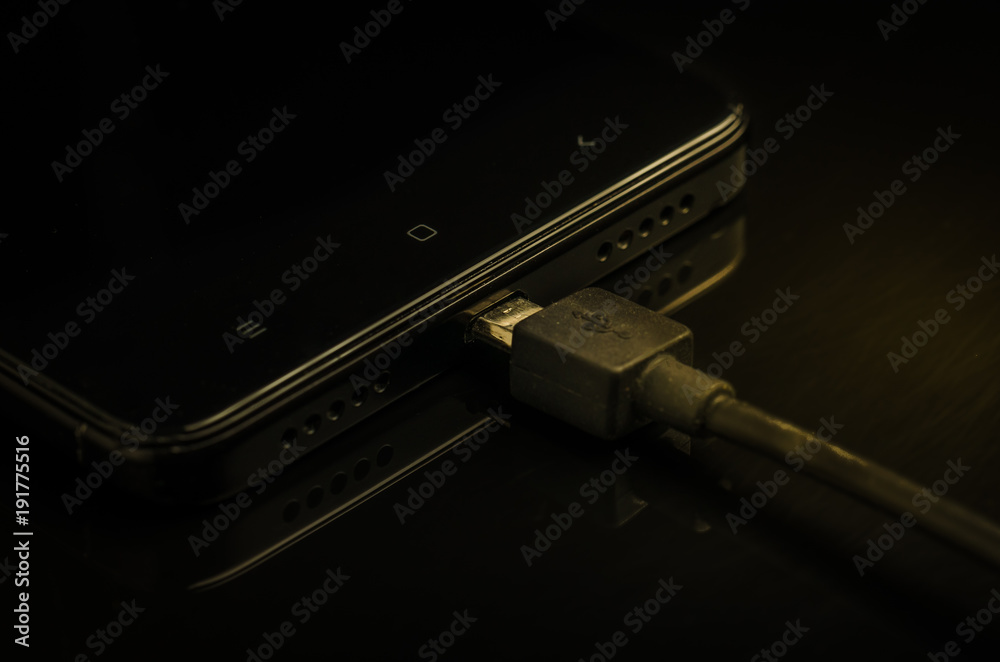 black Smartphone with charger on a black background/black Smartphone with charger on a black background. selective focus black Smartphone with charger on a black background/black Smartphone with charger on a black background. selective focus