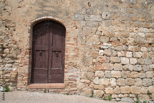 Tilted narrow  closed door in ancient stone wall  © David