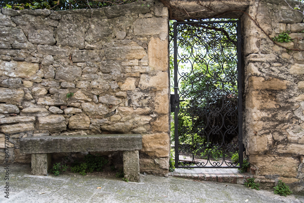 Fotografie Iron gate in ancient stone wall with bench