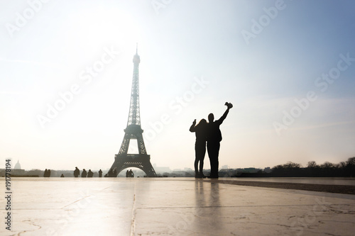 Couple at Eiffel Tower. Travelers and tourists exploring the world and the city of Paris. Romantic lovers on honeymoon or friends having fun. Silhouette people sightseeing. Wanderlust and travel. © terovesalainen