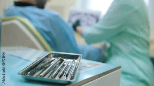 Doctor stomatologist and patient in the dental office, consulting, explanation and demonstration of x-ray, focus on instruments photo