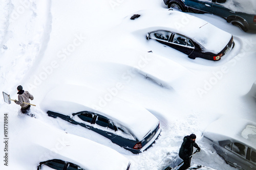 After a snowstorm, people dig out cars from under snow