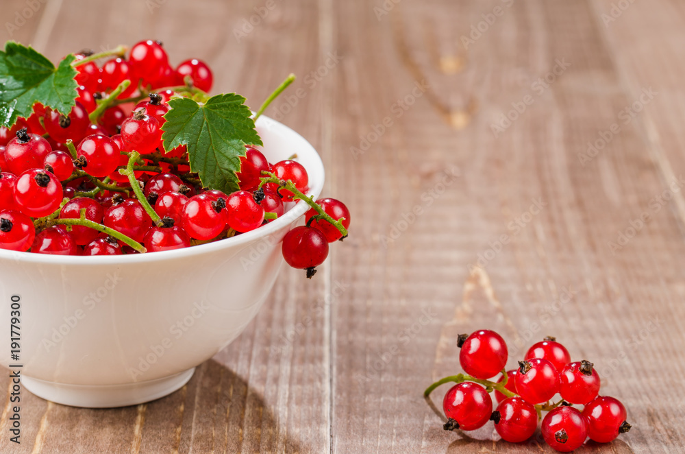 red currant in a white plate on a wooden background/red currant in a white plate on a wooden background. copy space red currant in a white plate on a wooden background/red currant in a white plate on a wooden background. copy space
