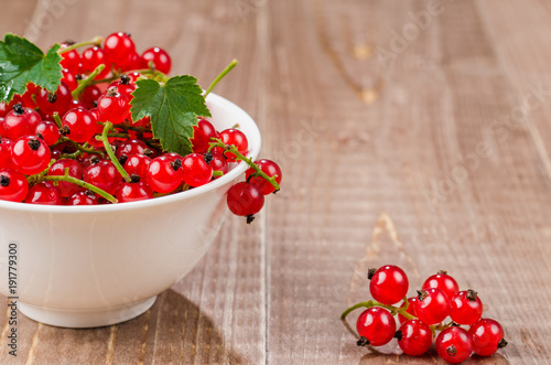red currant in a white plate on a wooden background/red currant in a white plate on a wooden background. copy space