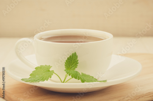 white cup of tea and leaves of mint on a wooden tray/white cup of tea and leaves of mint on a wooden tray. selective focus
