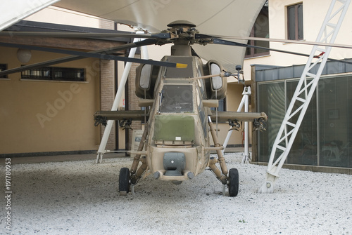 fuselage of a military helicopter used in war, metal, camouflage, with rivets, pilot cabin control, painted several times, old, exposed in a museum, symbols, green, beiges, Italy