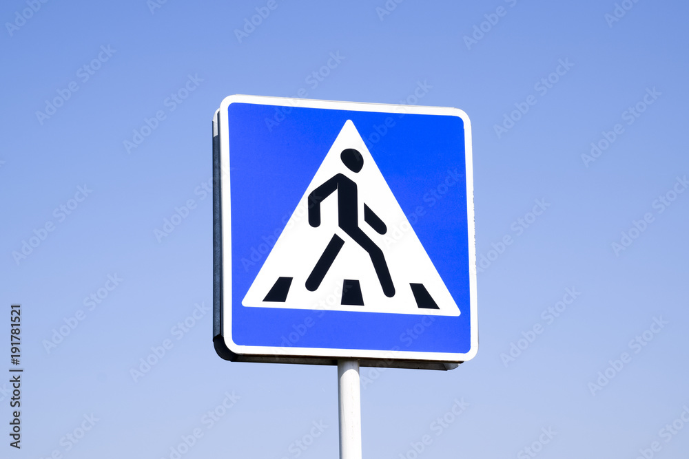 A pedestrian crossing sign. Sign on a blue sky background. A pedestrian crossing sign. Sign on a blue sky background.
