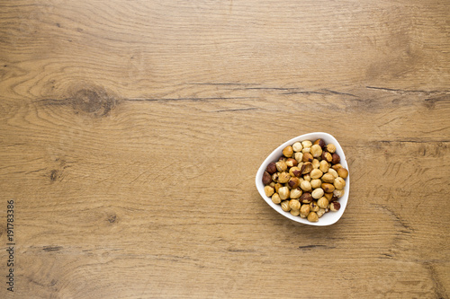 healthy raw hazelnuts in white bowl on wooden table
