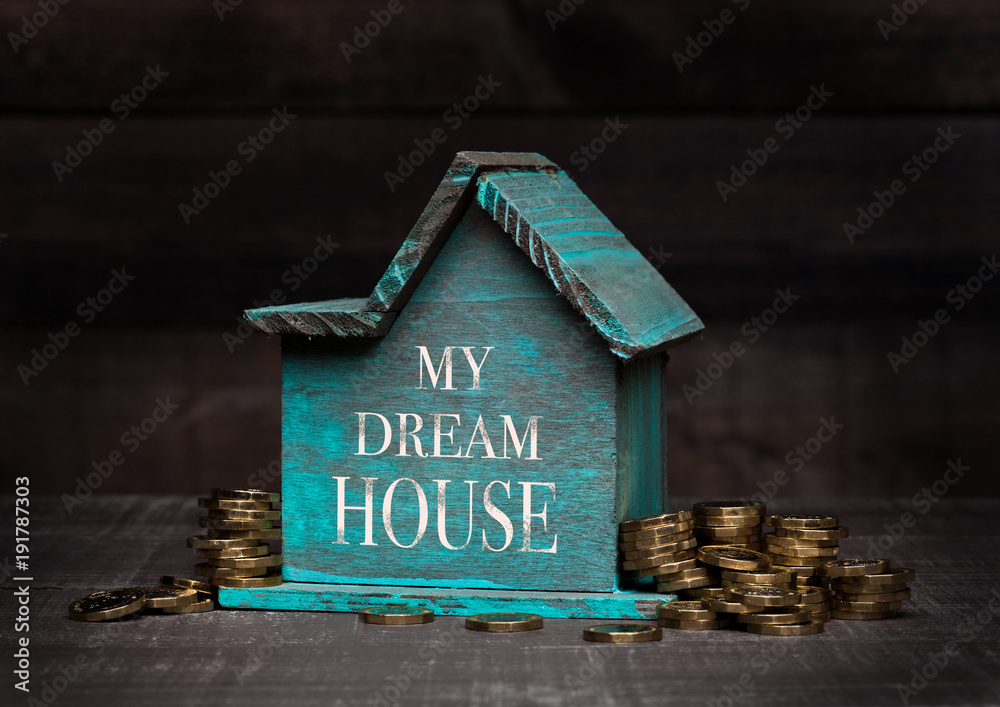 Wooden house model with coins next to it and hand Wooden house model with coins next to it and hand