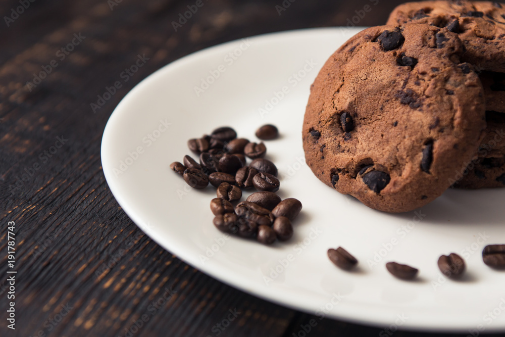 chocolate chip cookies on a white plate with coffee beans on dark wooden table chocolate chip cookies on a white plate with coffee beans on dark wooden table