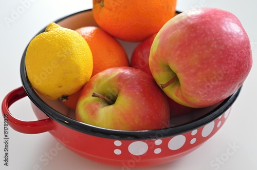 red vintage bowl with white dots including fresh fruits like apples, oranges, lemon, healthy food, vegan diet