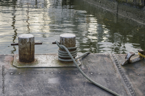 Detail of vintage ship deck with mooring rope and bollards in harbor of Rotterdam, Netherlands, illustrating vintage transport and seafaring.