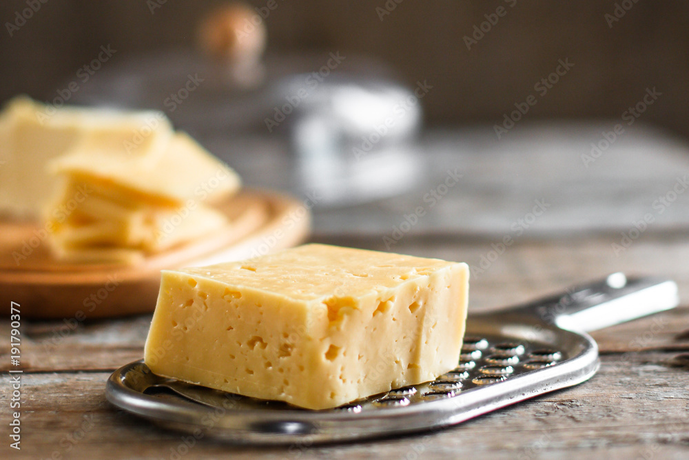 a piece of hard cheese and a grater on a wooden table