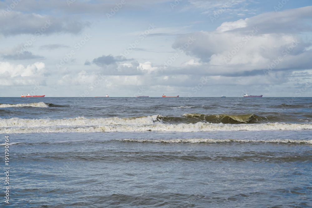 Low tide at Scheveningen beach near the Hague featuring sails on horizon under dark sky clouds. 