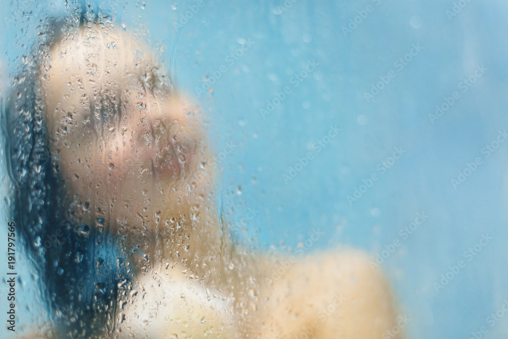 View of urecognizable young female model poses in shower cabine at bathroom, washes her luxurious hair, has wet body, blank copy space for your promotional text. Showering and bathing concept View of urecognizable young female model poses in shower cabine at bathroom, washes her luxurious hair, has wet body, blank copy space for your promotional text. Showering and bathing concept