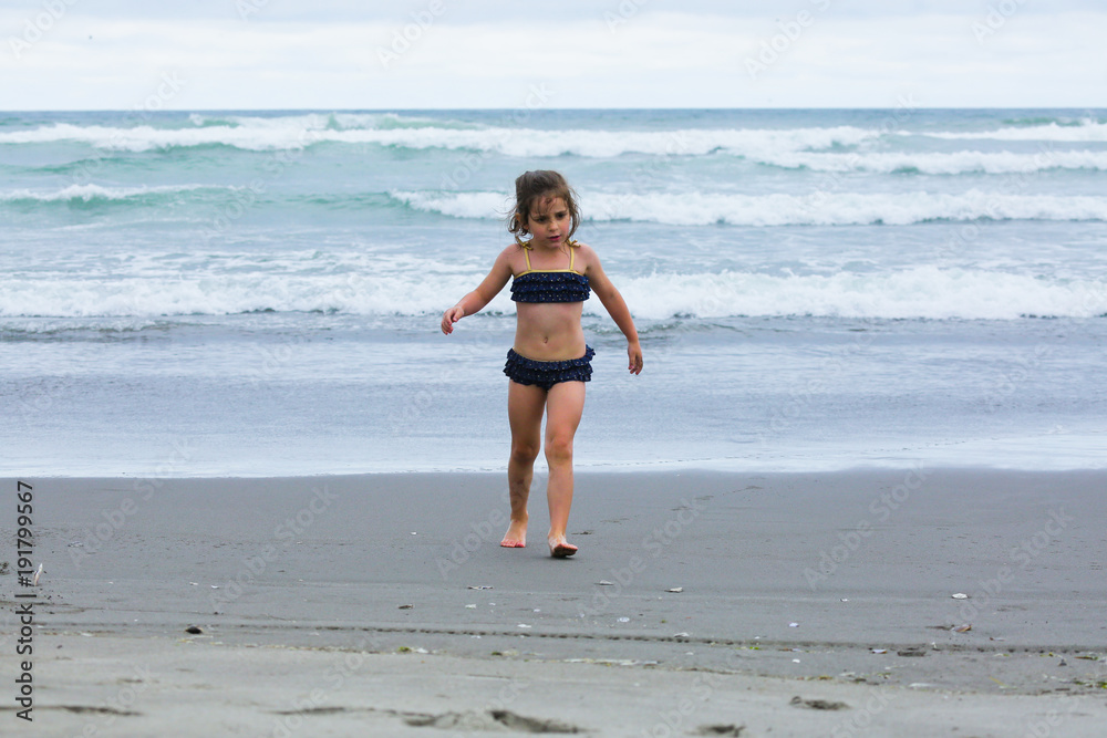 Very Brave Small 4 or 5 Years Girl  in preschool age walking in the Ocean with bright blue water, Pacific Ocean, Oregon Coast, USA, Family Vacation