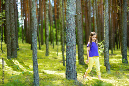 Cute little girl having fun during forest hike on beautiful summer day