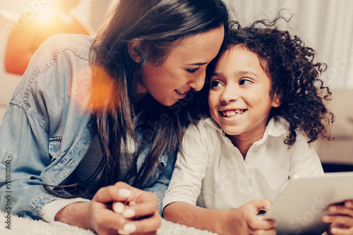 Mothers attention concept. Happy mom and kid disporting with modern technology at home. They are looking each other with fondness photo