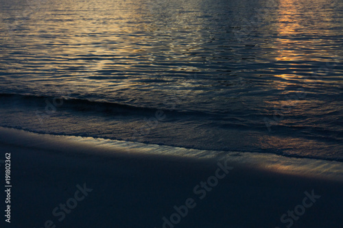 Dusk on the beach. Reflection of the sun in the calm sea. 