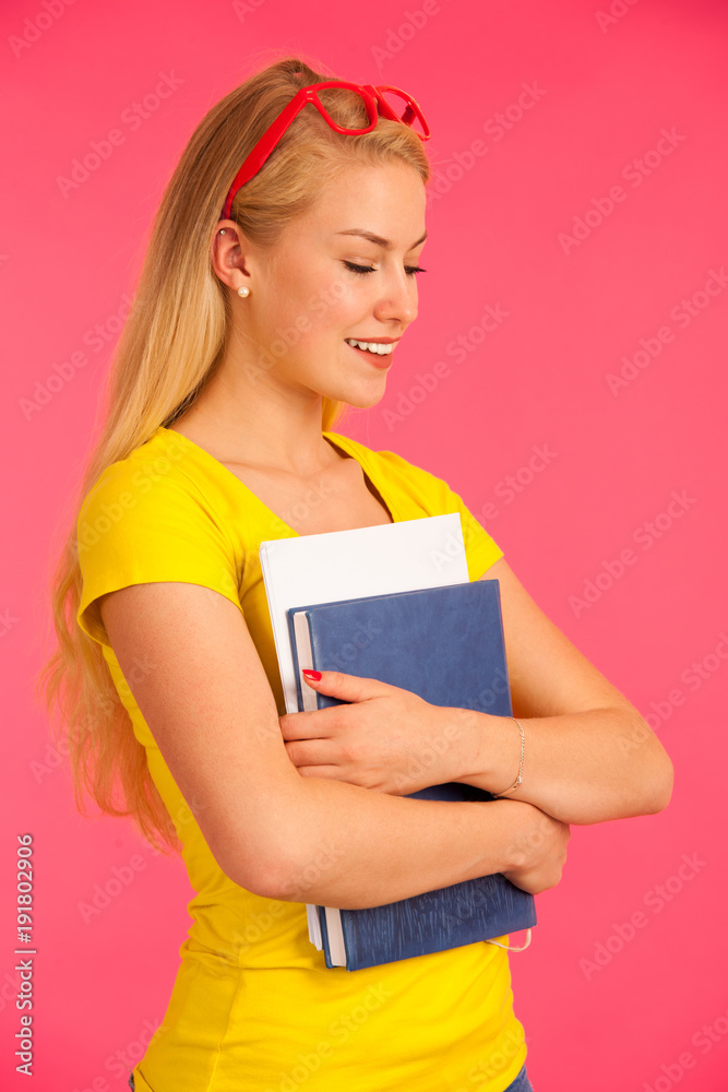 Beautiful young happy woman in yellow t shirt holds folder pose over pink background Beautiful young happy woman in yellow t shirt holds folder pose over pink background