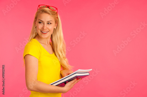 Beautiful young happy woman in yellow t shirt holds folder pose over pink background