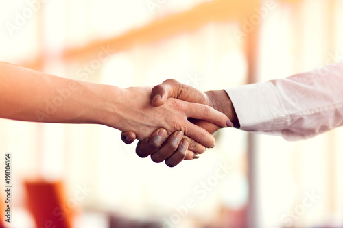 Closeup of White and Black shaking hands over a deal