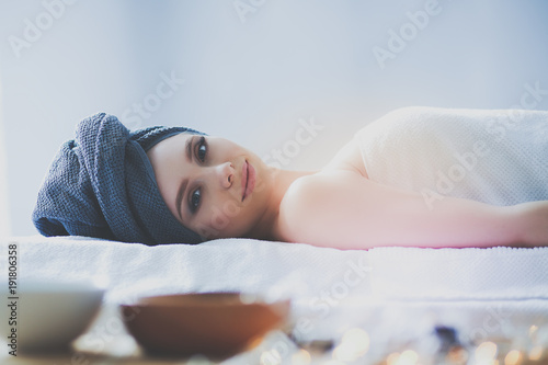 Young woman lying on a massage table,relaxing with eyes closed. Woman. Spa salon