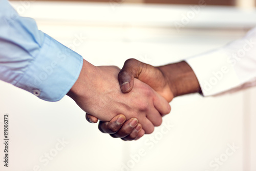 Closeup of White and Black shaking hands over a deal