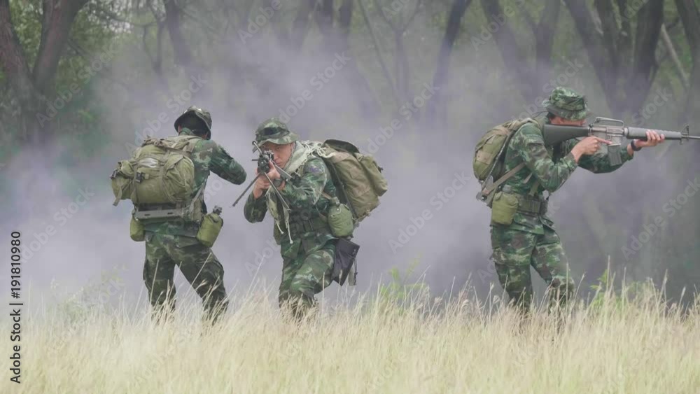Squad of Fully Equipped and Armed Soldiers moving through grass. Squad Moving Behind Him. Squad of Fully Equipped and Armed Soldiers moving through grass. Squad Moving Behind Him.