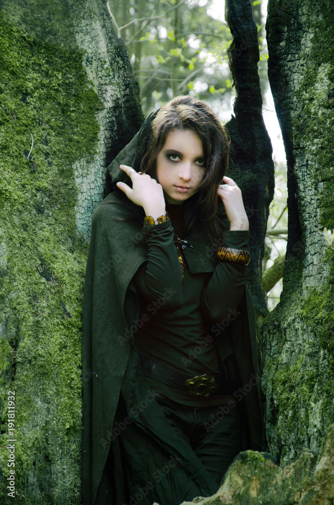 she-elf dressed in cloak with hood color of khaki in a dense the forest she-elf dressed in cloak with hood color of khaki in a dense the forest