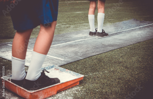 Students boy wait for queue and prepare himself for taking long jump on flour powder mark on sport competition day. School sports day competition activities concept for background.