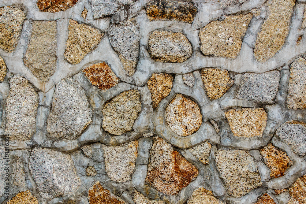 Fototapeta premium Close up view of old garden stone wall. Pattern with vertical natural lines and a grey rough surface in background. Wall made of blocks of stones. Abstract composition.